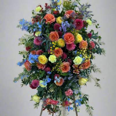 Tall standing floral spray with multicolored roses and mixed blooms
