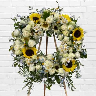 Large floral wreath with white roses and sunflowers on a stand