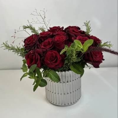 Red rose arrangement in a ribbed silver vase with green accents