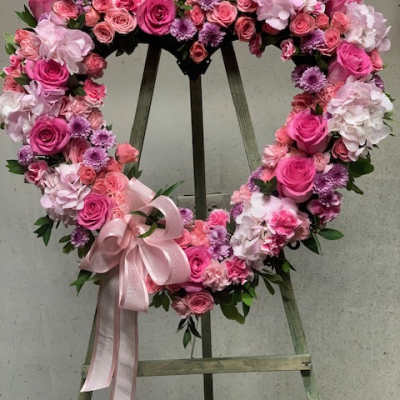 Heart-shaped floral wreath of pink roses and hydrangeas with a ribbon bow