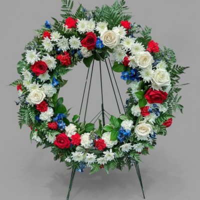 Circular floral wreath on a stand with red, white, and blue flowers