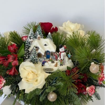 Christmas floral arrangement with white and red roses and a snowy village ornament