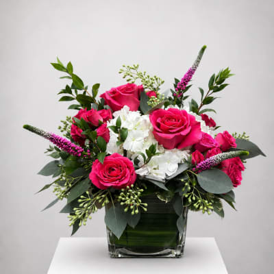 Pink roses and white hydrangeas in a glass vase with greenery