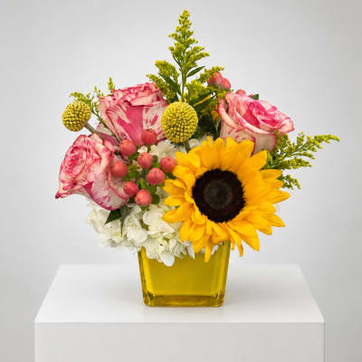 Bouquet of pink roses and a sunflower in a yellow vase