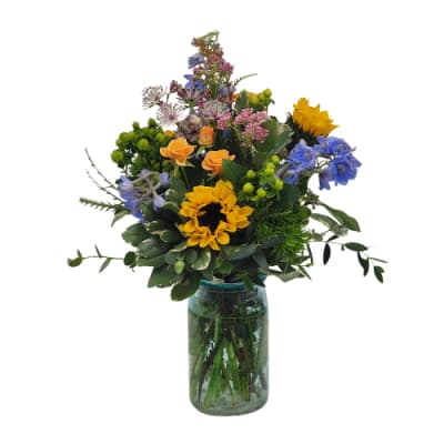 Mixed bouquet with sunflowers, blue flowers, and orange roses in a glass vase