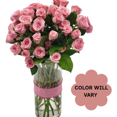 Pink roses arranged in a clear glass vase with a pink ribbon
