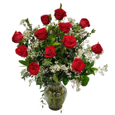 Red roses arranged in a clear glass vase with white filler flowers