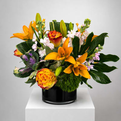 Orange lilies and roses arranged in a black vase