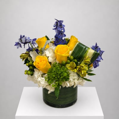 Yellow roses and blue flowers arranged in a green vase