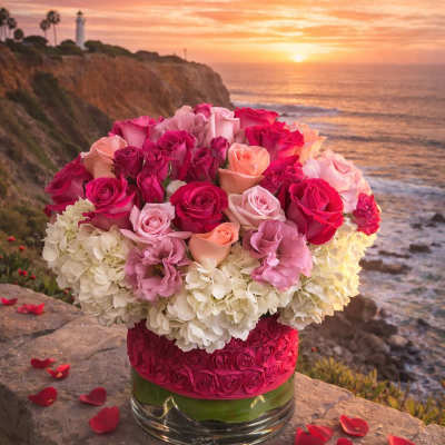 Pink and peach roses arranged with white hydrangeas in a glass vase