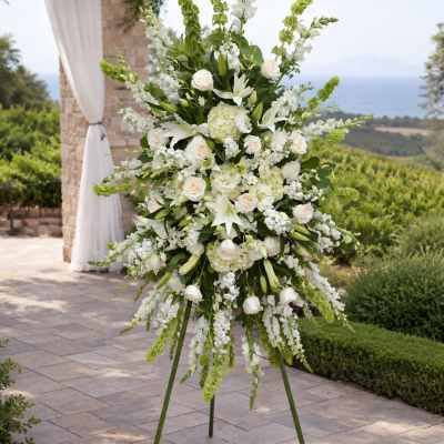 Tall white floral arrangement on a stand outdoors