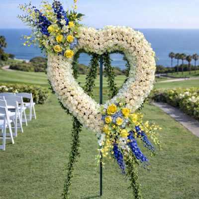 Heart-shaped floral wedding arch with white, yellow, and blue flowers