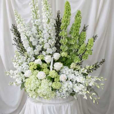Large white and green floral arrangement in a white container