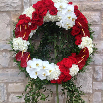 Circular funeral wreath of red roses, white orchids, and white hydrangeas