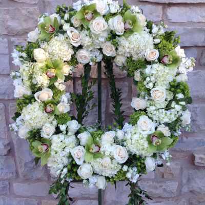 White floral wreath on a stand with roses and orchids