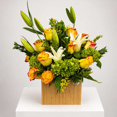 Yellow and white roses with lilies in a wooden box