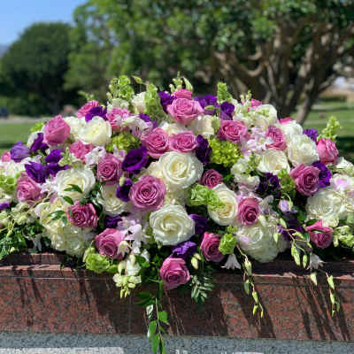 Large arrangement of pink, white, and purple roses on a stone ledge
