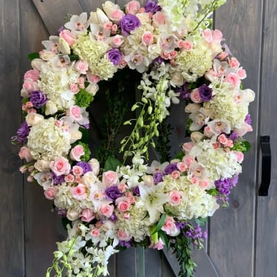 Large floral wreath with pink, white, and purple blooms on a wooden backdrop