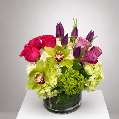 Pink roses and green orchids arranged in a glass vase