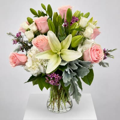 Pink roses and white lilies arranged in a clear glass vase