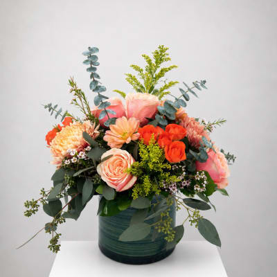 Peach and orange rose bouquet in a green vase