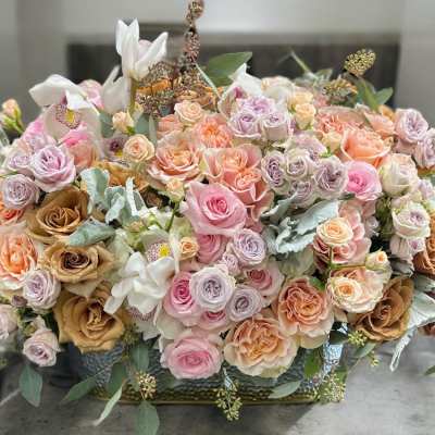 Large pastel bouquet of roses and orchids in a low container