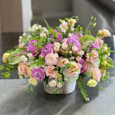 Mixed pink and peach floral arrangement in a white vase