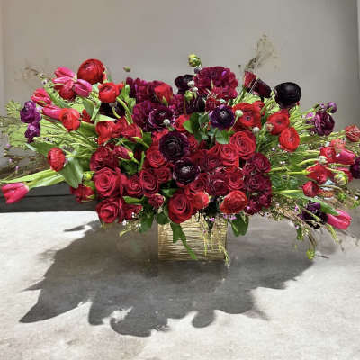 Large red and burgundy floral arrangement in a gold rectangular vase