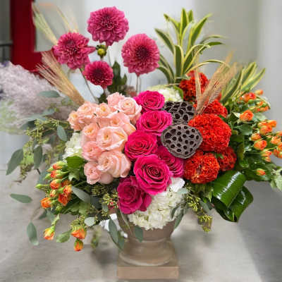 Mixed floral arrangement in a pedestal vase with pink, peach, and orange blooms