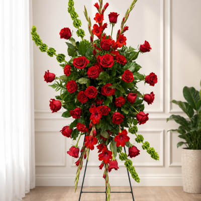 Tall standing arrangement of red roses and red flowers with green accents