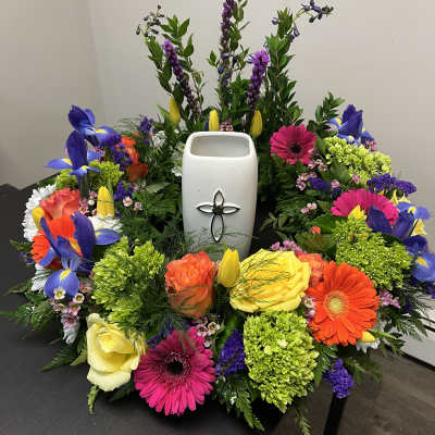 Colorful floral wreath around a white urn with a cross emblem
