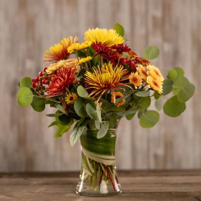 Bouquet of yellow, orange, and red chrysanthemums in a glass vase