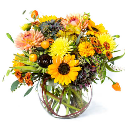 Mixed bouquet of sunflowers, dahlias, and chrysanthemums in a clear glass vase