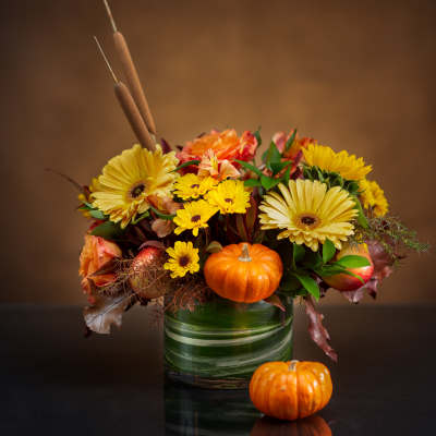 Autumn bouquet with yellow daisies and orange roses in a glass vase