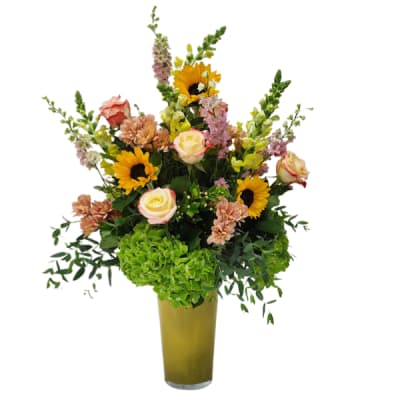 Mixed bouquet with sunflowers, roses, and pink blooms in a tall vase