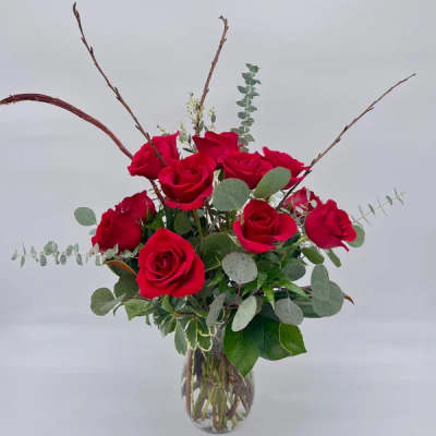Arrangement of red roses with eucalyptus in a clear glass vase