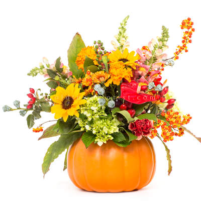 Fall bouquet in a pumpkin container with sunflowers and orange blooms