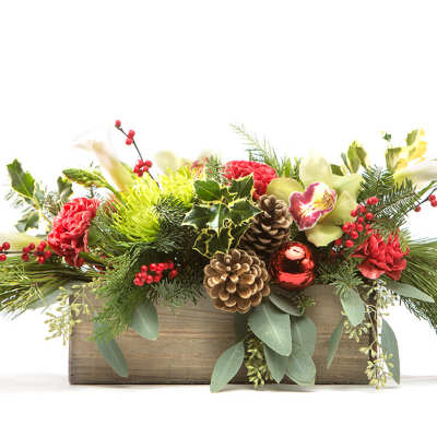 Holiday floral arrangement in a wooden box with pinecones and red blooms