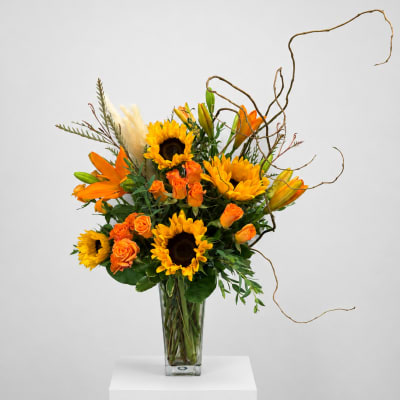 Orange and yellow floral arrangement in a clear glass vase