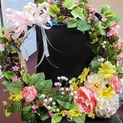 Floral wreath with pink ribbon, yellow daisies, and pink-and-white blooms