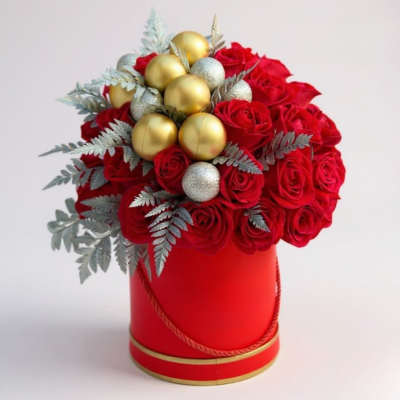 Red roses arranged in a red hat box with gold ornaments and silver foliage