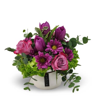 Pink and purple flowers in a white pot with a LOVE tag
