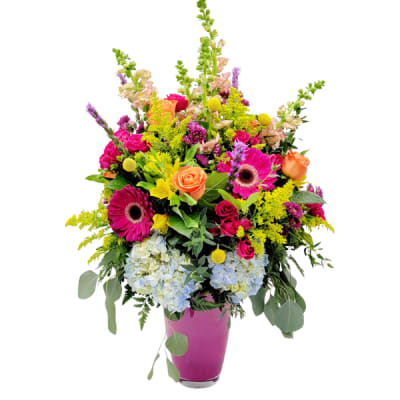 Colorful mixed bouquet in a pink vase with roses, gerbera daisies, and hydrangeas