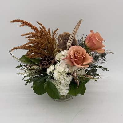 Peach roses and white hydrangeas in a glass bowl with dried accents