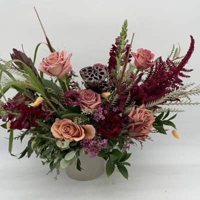 Mixed bouquet of pink roses and burgundy flowers in a white vase