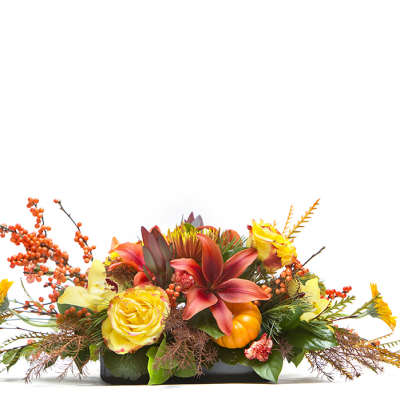 Low floral arrangement with yellow roses, orange lilies, and autumn berries in a black container