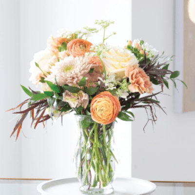 Peach and white flowers arranged in a clear glass vase