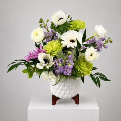 White and lavender floral arrangement in a white textured vase