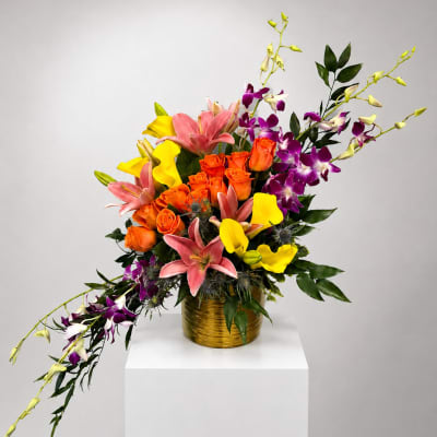 Colorful bouquet of roses, lilies, and orchids in a gold vase