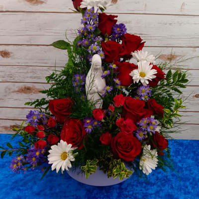 Red roses and white daisies arranged with purple asters in a white vase